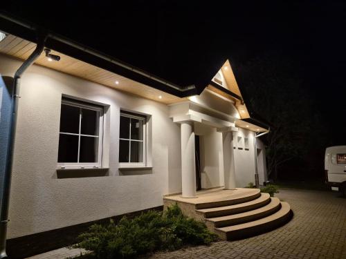 a white house with stairs in front at night at Domek na Mazurach-Piasutno in Piasutno