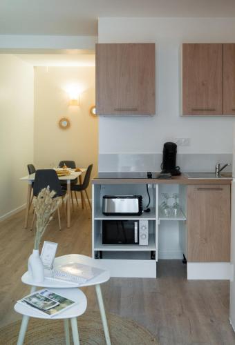 une petite cuisine avec une table et un micro-ondes dans l'établissement Sémillon - Baignoire Balnéo plein centre, à Bergerac