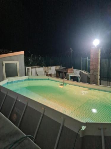 an empty swimming pool at night with a light at Casa Nadiia in Cinisi
