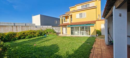 a yellow house with a lawn in the yard at Oceans House Villa in Carcavelos