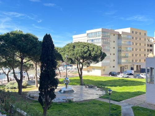 un parc avec une fontaine et des arbres devant un bâtiment dans l'établissement À Deux Pas de la Mer charmant T2, à Canet