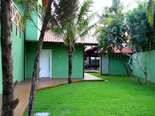 a green house with palm trees in front of it at Posada Sueños De Verano in Florianópolis