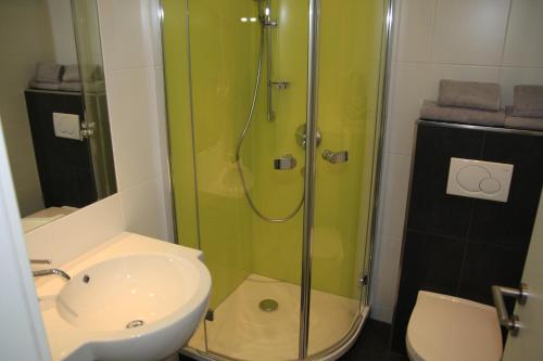 ein Bad mit einer Dusche, einem Waschbecken und einem WC in der Unterkunft Seehotel Lilly in Strobl