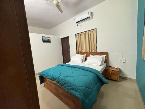 a bedroom with a bed with a blue comforter at Tranquil Trails-Nashik in Nashik