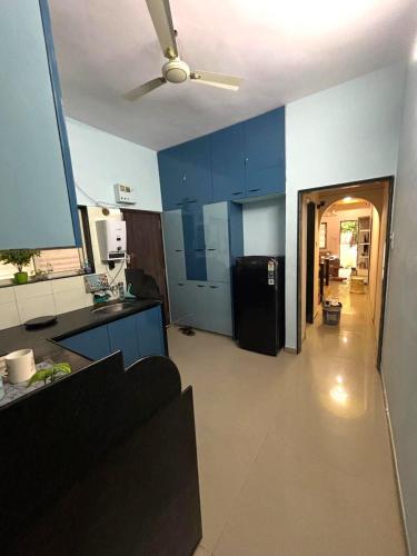 a kitchen with blue cabinets and a black refrigerator at Tranquil Trails-Nashik in Nashik
