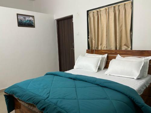 a bed with a blue comforter in a bedroom at Tranquil Trails-Nashik in Nashik
