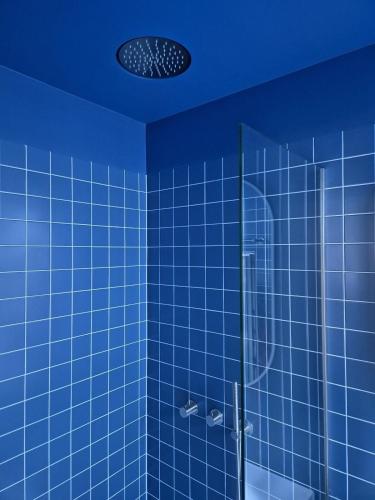 a blue tiled bathroom with a glass shower at Suite Palette in Amsterdam