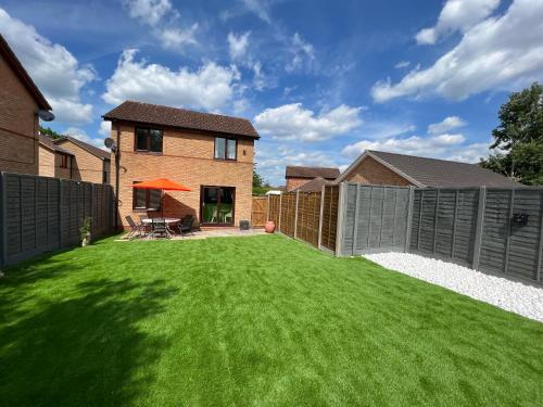 a backyard with a green lawn and a fence at The Little Chinoiserie 2 bed house with large garden and only 7 min away from MK Central Rail station and City Centre in Milton Keynes