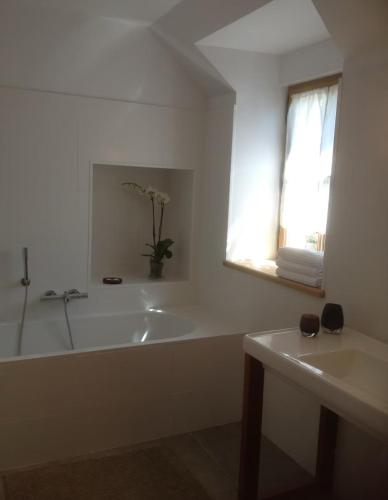 La salle de bains blanche est pourvue d'une baignoire et d'une fenêtre. dans l'établissement Le hameau des vignes, à Saint-Julien-de-Chédon
