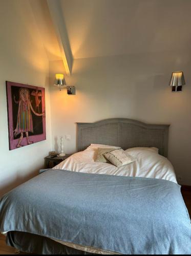 une chambre avec un lit et un tableau au mur dans l'établissement Le hameau des vignes, à Saint-Julien-de-Chédon