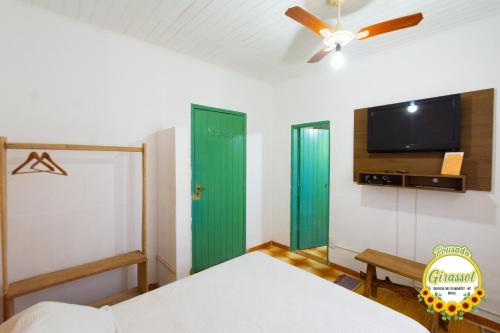 a bedroom with a bed and a flat screen tv at Pousada Girassol in Chapada dos Guimarães