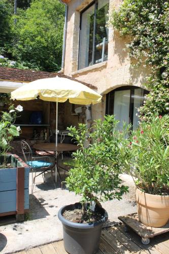a patio with a table and an umbrella at Chambres d'hôtes Par Hasard in Saint-Bressou