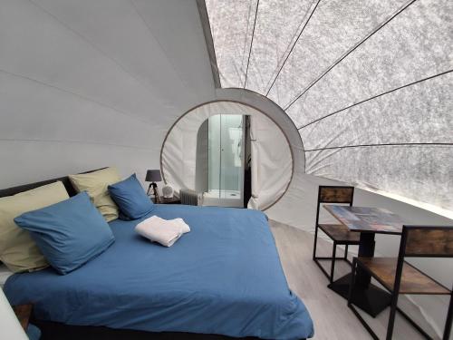 - une chambre avec un lit bleu et un miroir rond dans l'établissement La Bubble, à La Salvetat-Peyralès