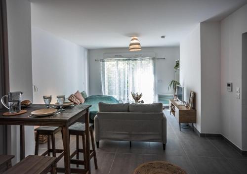 un salon avec une table et un canapé dans l'établissement Terrasse, Soleil et Confort - Studio Neuf à Montpellier, à Montpellier