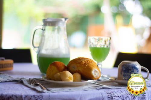 a table with a plate of food and a jug of green juice at Pousada Girassol in Chapada dos Guimarães