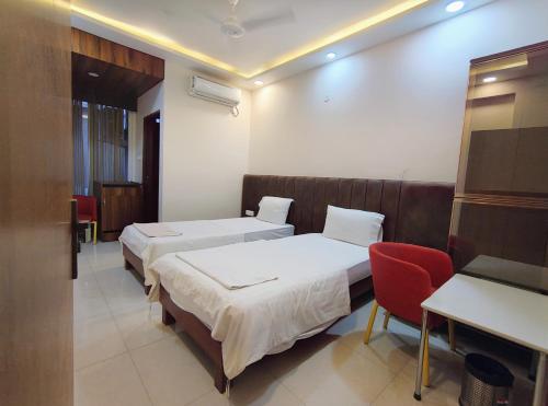 a hotel room with two beds and a red chair at Shree 9NB Hotels, Pithampur in Indore