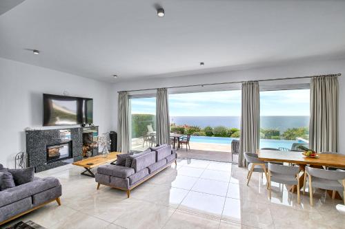 a living room with a fireplace and a table and chairs at Olymp Luxury Villa D - Luxury Escape with Direct Beach Access and Unique Sunsets in Paphos