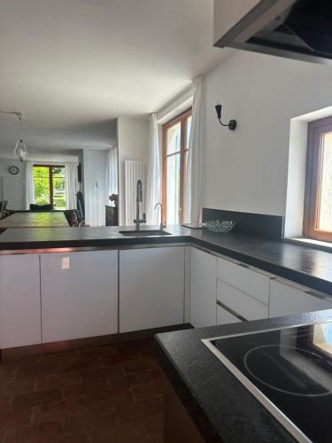 a kitchen with white cabinets and black counter tops at Collina di Sopra in Tresana