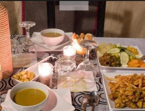 a table topped with bowls of soup and plates of food at Fantastic desert camp in Oulad Akkou