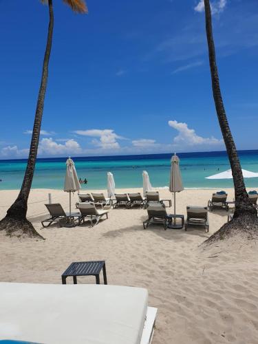 a beach with chairs and umbrellas and the ocean at Casa Madi in Bayahibe