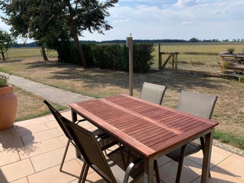 a wooden table and chairs on a patio at Idyllisches Ferienhaus in ruhiger Lage in Wölsickendorf-Wollenberg