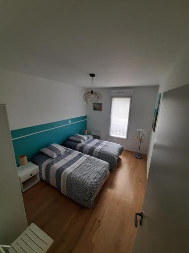 une chambre avec deux lits et une fenêtre dans l'établissement Les Sables d'or, à Fréhel