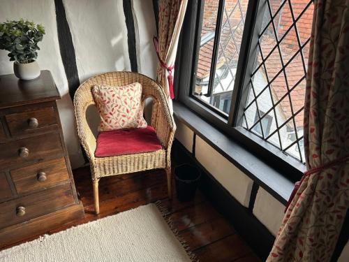 a wicker chair sitting in a room with a window at Step back in time in Rye