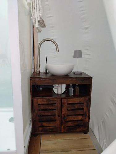 La salle de bains est pourvue d'un lavabo en bois. dans l'établissement La Bubble, à La Salvetat-Peyralès