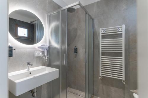 a bathroom with a sink and a shower with a mirror at Hotel Cristina in Rimini