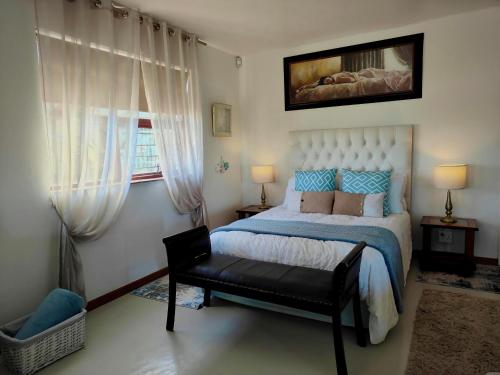 a bedroom with a bed and a chair and a window at Sand Sittie in Sandbaai