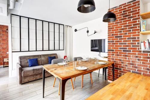une salle à manger avec une table en bois et un mur en briques dans l'établissement Maison dartiste a proximite de la gare de Lyon, à Paris
