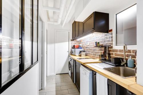 - une cuisine avec un évier et un mur en briques dans l'établissement Maison dartiste a proximite de la gare de Lyon, à Paris