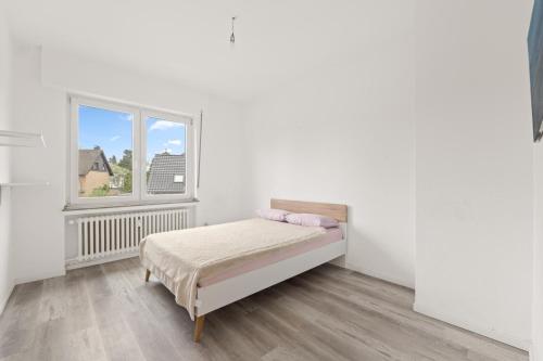 a white bedroom with a bed and a window at Geräumiges Familienhaus Köln in Niederdorla