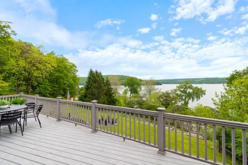 a deck with tables and chairs and a view of a lake at The Gallagher House - Speakeasy Firepit Lakeview in Hammondsport