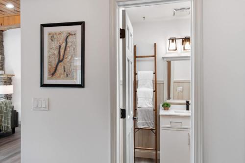 a white hallway with a bathroom with a mirror at The Gallagher House - Speakeasy Firepit Lakeview in Hammondsport