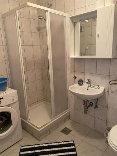 a bathroom with a shower and a sink and a washing machine at Beach Apartments Luka in Tribanj-Krušćica