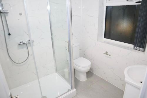 a white bathroom with a shower and a toilet at 5BDR Spacious En-suite Accomodation in Coventry