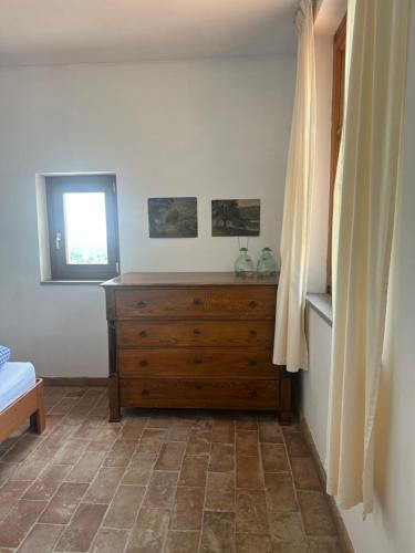 a bedroom with a wooden dresser and a window at Collina di Sopra in Tresana