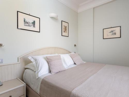 a white bedroom with a bed and two pictures on the wall at Hotel Gardenia Sorrento, Ascend Hotel Collection in Sorrento