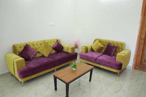 two couches in a living room with purple and yellow at Maitree Serenity Farm Stay 