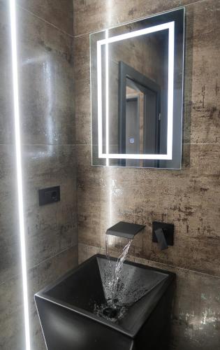 a bathroom with a black sink and a mirror at Luna Apartments B in Suceava