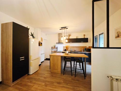 a kitchen with a wooden table and a refrigerator at Maison paisible proche centre avec piscine in Angoulême