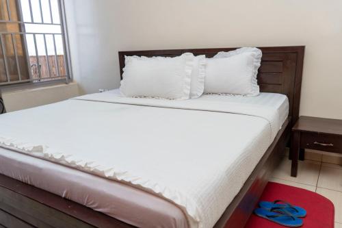 a bedroom with a bed with white sheets and a window at Kigali Green View Apartments in Kigali