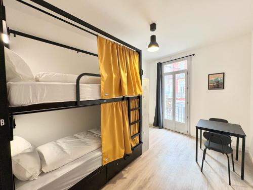 a room with two bunk beds and a desk at Lourdes Backpackers in Lourdes