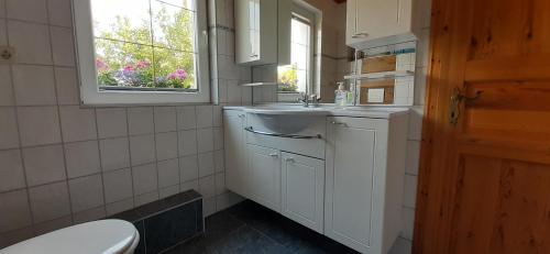 a bathroom with a sink and a toilet and a window at Kleines Ferienhaus Heyne in Rerik