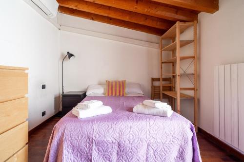 a bedroom with a purple bed with towels on it at TAKE OFF Airport House in Orio al Serio