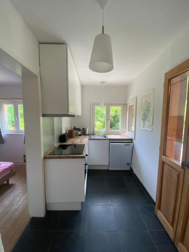 une cuisine avec des placards blancs et un sol noir dans l'établissement Logement individuel 3 pièces dans chalet, à Glières-Val-de-Borne