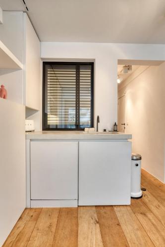 an empty kitchen with white cabinets and a window at StudioV in Knokke-Heist