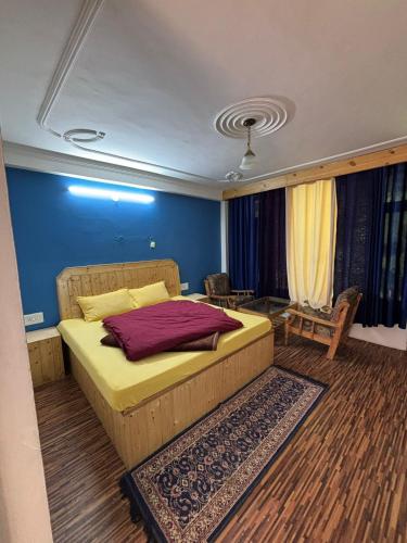 a bedroom with a bed and a blue wall at Asha Cottage in Manāli