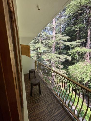 a balcony with a chair and a view of trees at Asha Cottage in Manāli